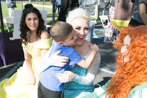 Kylee McGrane '17 hugs a child, while dressed as A Moment of Magic princess.